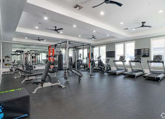 A spacious gym with various exercise equipment and a digital fitness tracker.