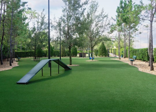 a park with a slide and benches on the grass at The Oasis at Moss Park, Orlando, FL, 32832