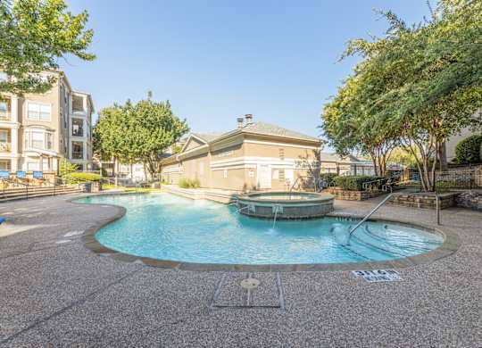 Swimming pool with a hot tub that has small fountain features at Encore at Buckingham apartments in Richardson, TX