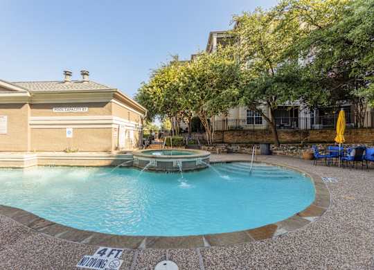Swimming pool with a hot tub with small fountain feature and seating in the area at Encore at Buckingham apartments in Richardson, TX