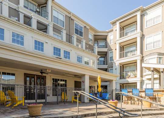 Patio area beside the pool with seating and a grilling station at Encore at Buckingham apartments in Richardson, TX