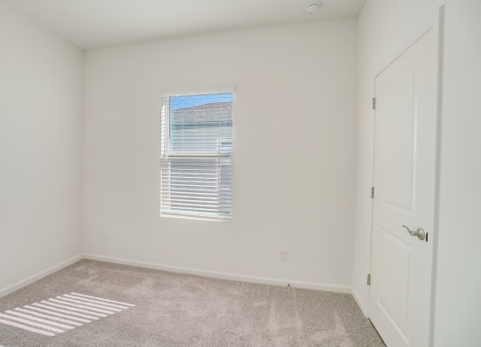 Bedroom with window and closet door in the Oak floor plan at Beacon at Clinton Corners in Dade City, FL