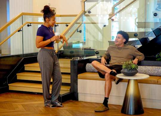A man and a woman are standing in a room with a staircase.