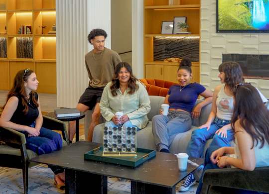 A group of people are sitting around a table in a room with a television in the background.