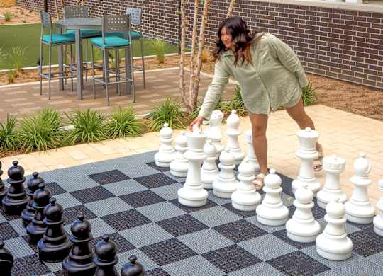 A woman playing a game of chess outdoors.