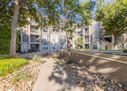 Walking paths within our community with lush trees at Encore at Buckingham apartments in Richardson, TX