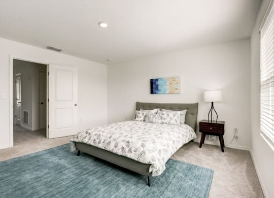 Alternate view of master bedroom with blue rug and bed at Beacon at Arbours in Ruskin, FL