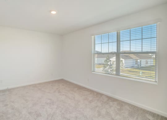 Bedroom with large window in the Verbena floor plan at Beacon at Clinton Corners in Dade City, FL