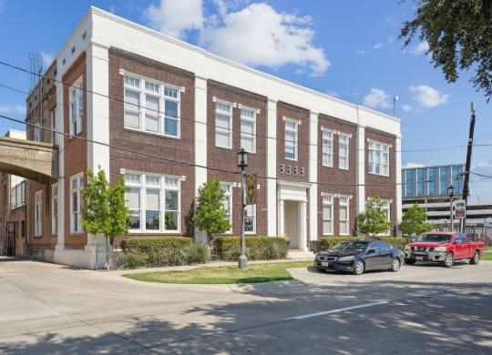 Street view of historic 3333 Elm Street Lofts Building with brick accents and large windows | Deep Ellum Lofts in Dallas, TX