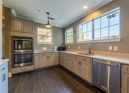 Community kitchen in the grand ballroom with stainless steel appliances, an oven, and coffee machine at Encore at Buckingham apartments in Richardson, TX