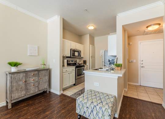 Model apartment kitchen area with short stool and wood-like flooring at Encore at Buckingham apartments in Richardson, TX