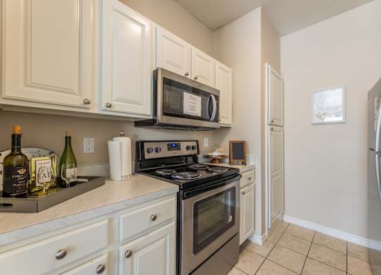 Model apartment kitchen with stainless steel appliances and white cabinets at Encore at Buckingham apartments in Richardson, TX