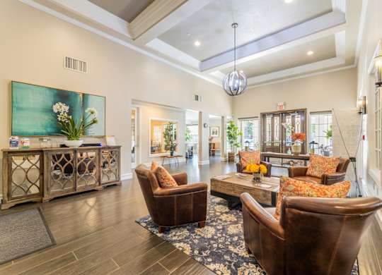 Waiting area with leather seats and a coffee table at the entrance to the leasing office at Encore at Buckingham apartments in Richardson, TX