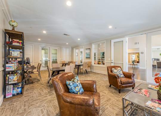 Cozy game room with leather single seat couches, tables and chairs, and a computer center at Encore at Buckingham apartments in Richardson, TX