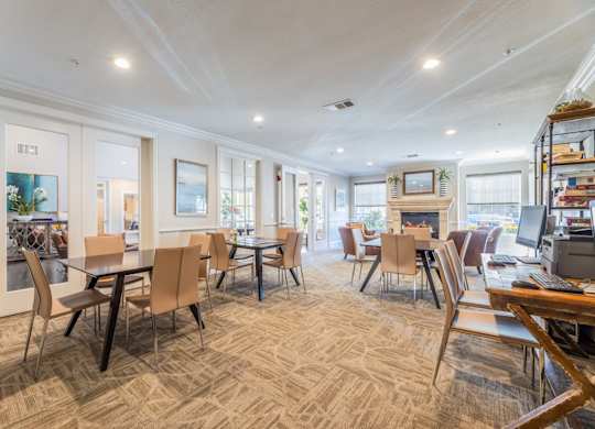 Game room with board games, computers and a printer, and plush seats by a fireplace at Encore at Buckingham apartments in Richardson, TX