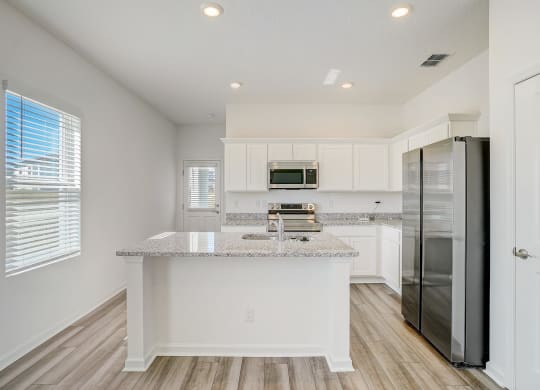 Kitchen with white cabinets, granite countertops, and stainless steel appliances in the Elm floor plan at Beacon at Clinton Corners in Dade City, FL