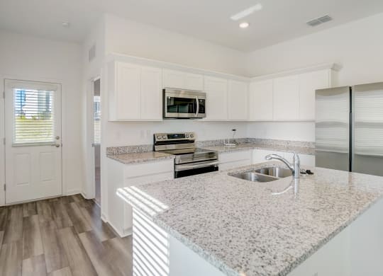 Kitchen with granite counter tops and kitchen island in the Elm floor plan at Beacon at Clinton Corners in Dade City, FL