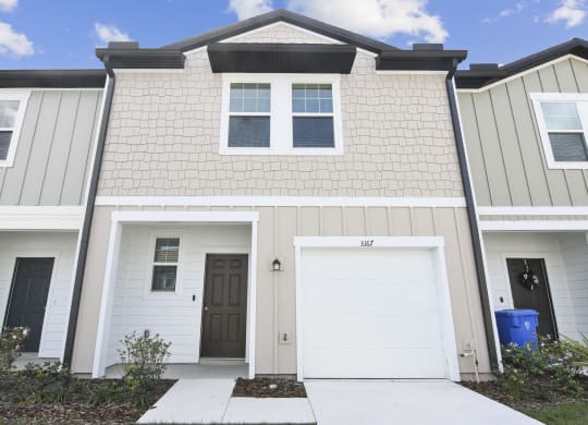 townhome with white siding and a white garage door at Beacon at Arbours, Florida, 33570