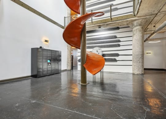 Amazon Hub package lockers in atrium next to chute centerpiece from old Ford assembly | Adam Hats Lofts from Deep Ellum Lofts in Dallas, TX