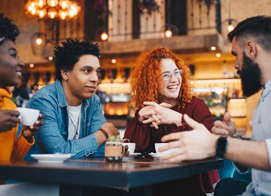 A group of friends are sitting around a table in a cafe.