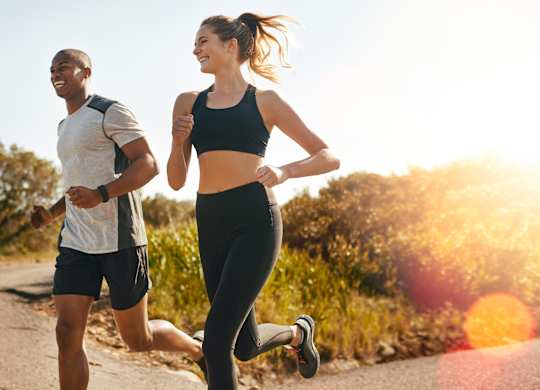 A man and a woman are jogging on a road.