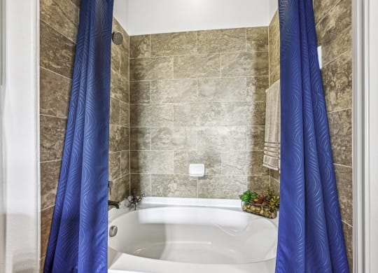 Modern bathroom with tiled bathtub at Allusion at West University apartments in Houston, TX