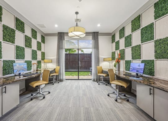 A modern business center with individual workstations and decorative wall panels at Allusion at West University apartments in Houston, TX