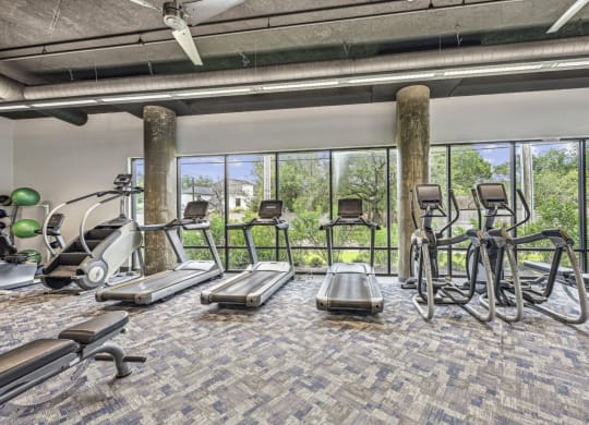 Fitness center with treadmills, elliptical machines, and a stair climber at Allusion at West University apartments in Houston, TX
