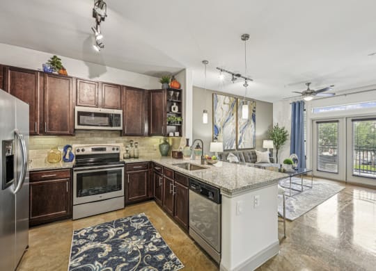 Kitchen view showing a spacious layout with dark wood cabinets and pendant lighting at Allusion at West University apartments in Houston, TX