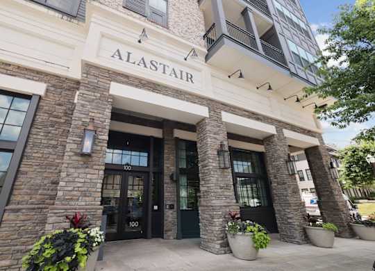 The Alastair at Aria Village leasing office entrance with stone brick pillars and potted flowers in Sandy Springs, GA