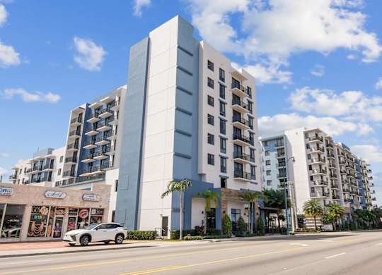 A modern building with a white facade stands on a street corner.