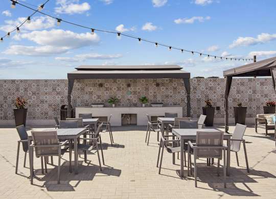 A patio with tables and chairs and a wall with tiles.