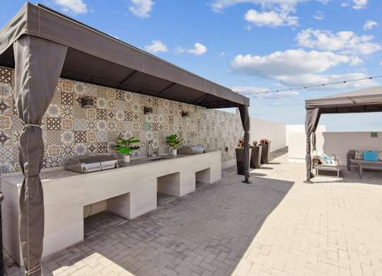 A patio area with a bench, a wall with tiles and a sculpture.