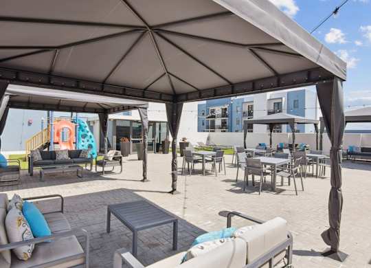 A patio area with tables and chairs under a large umbrella.