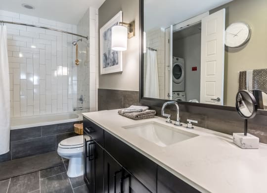 Large apartment bathroom with grey tile interior at The Case Building in Dallas, TX