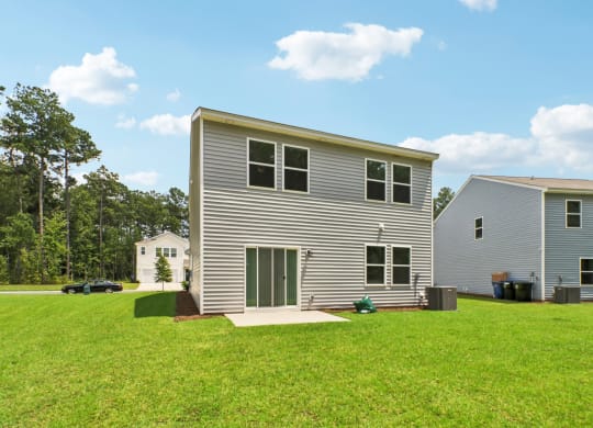 Spacious backyard with a well-maintained lawn and sliding glass doors at Beacon at Ashley River Landing in Summerville, SC