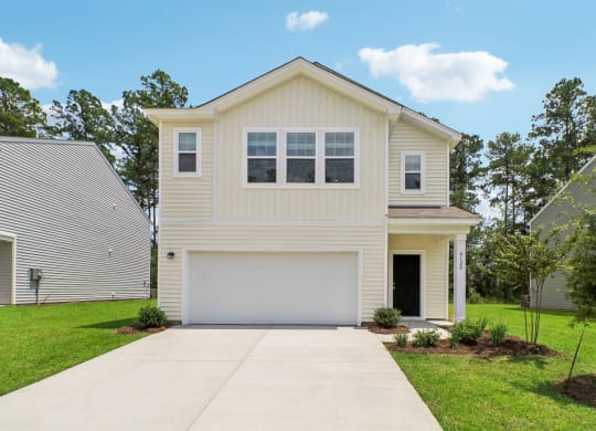 Front exterior view of the apartment with a two-car garage and well-kept lawn at Beacon at Ashley River Landing in Summerville, SC