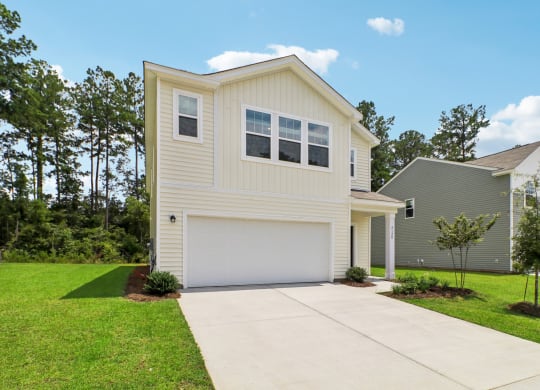 Entrance view of the house with a driveway and landscaped garden at Beacon at Ashley River Landing in Summerville, SC
