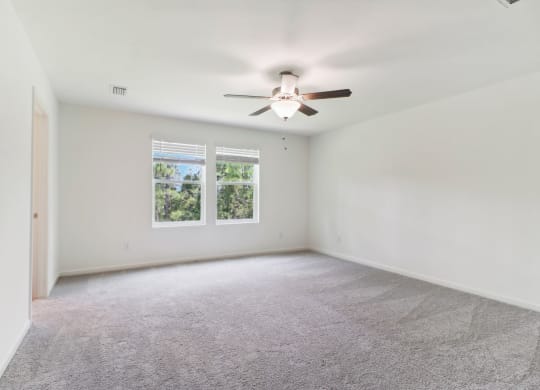 Large master bedroom with ceiling fan and carpet flooring at Beacon at Ashley River Landing in Summerville, SC