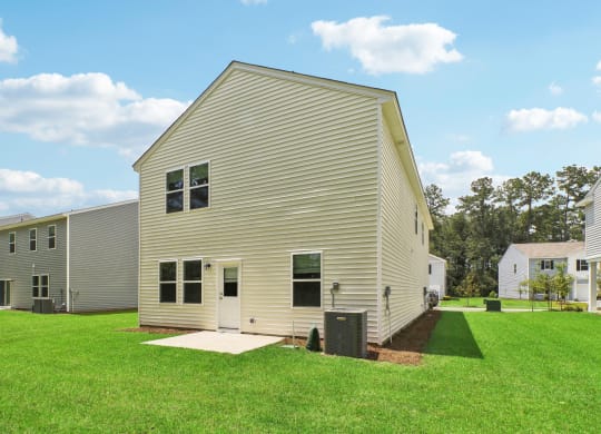 Side view of the house showcasing the expansive backyard and neighboring houses at Beacon at Ashley River Landing in Summerville, SC