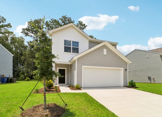 Another front view of a two-story house with a gray and white exterior and a landscaped front yard at Beacon at Ashley River Landing in Summerville, SC