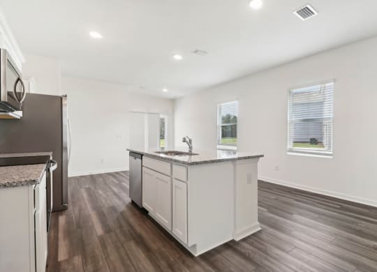 Oak white kitchen with a large island and granite countertop at Beacon at Ashley River Landing in Summerville, SC