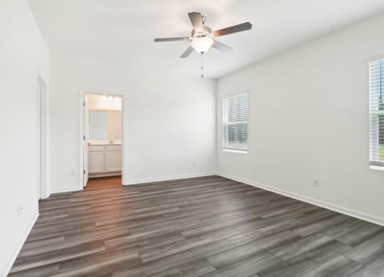 Oak master bedroom with white walls and ceiling fan at Beacon at Ashley River Landing in Summerville, SC