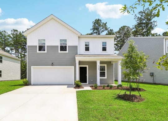 Sycamolre white and gray house with a lawn and a driveway at Beacon at Ashley River Landing in Summerville, SC