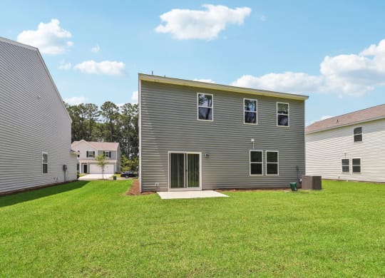 Sycamore backyard with a gray house and a green lawn at Beacon at Ashley River Landing in Summerville, SC