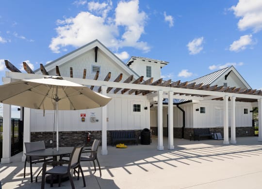 a patio with a table and chairs and a white building in the background at Beacon at Ashley River Landing, Summerville, 29485
