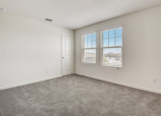 a bedroom with a door and two windows at Beacon at Meridian, San Antonio, TX