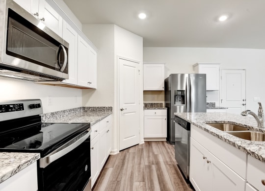 a kitchen with white cabinets and black appliances at Beacon at Meridian, Texas