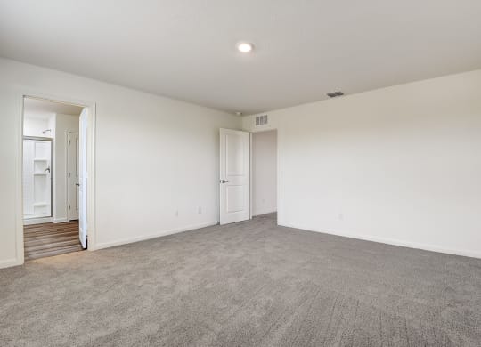 a Master bedroom connected to bathroom with white walls and carpet
