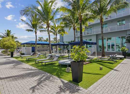 A sundeck area with loungers, shaded seating areas, and lush palm trees at Blue Lagoon 7 Apartments in Miami, FL